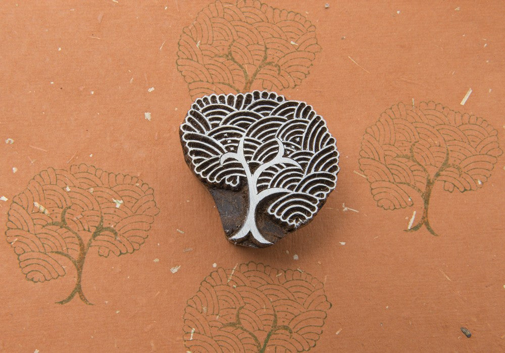 A decorative stamp with a design of a rain tree, predominantly gray in color, placed on an orange background with leaf patterns.
